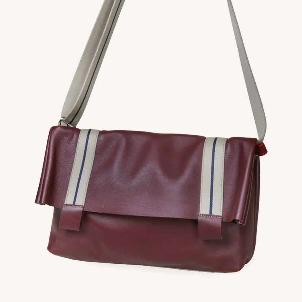 Sac reporter à rabat bordeaux en cuir sur fond beige